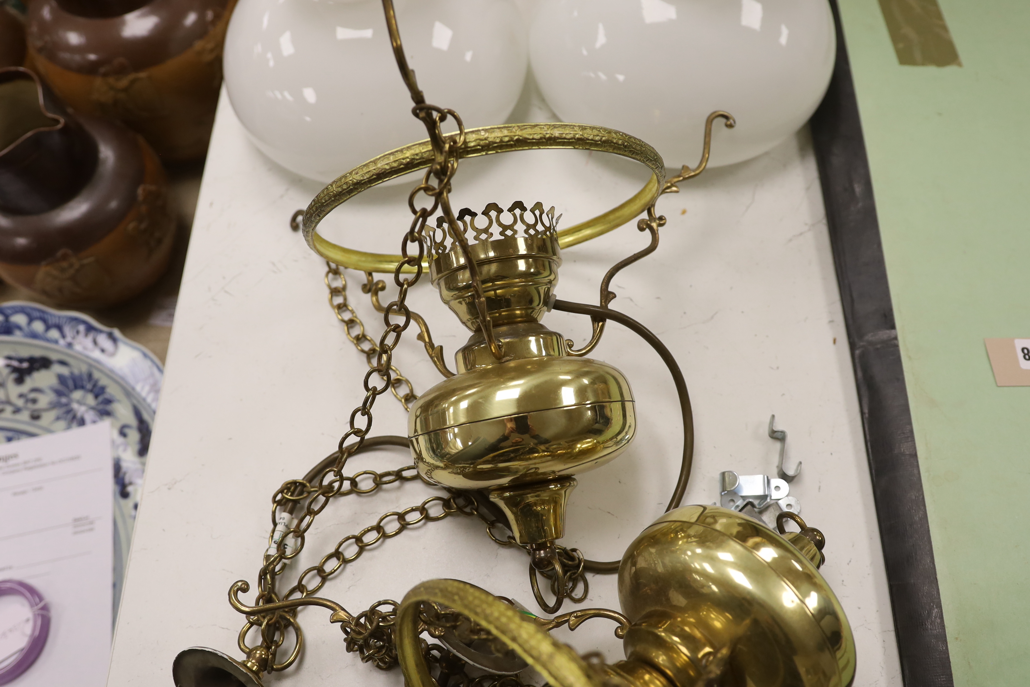 A pair of brass hanging lights with opaque glass shades
